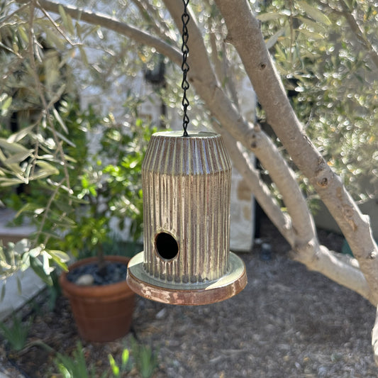 Green fluted ceramic birdhouse handcrafted from stoneware with black acrylic base, hanging outdoors.